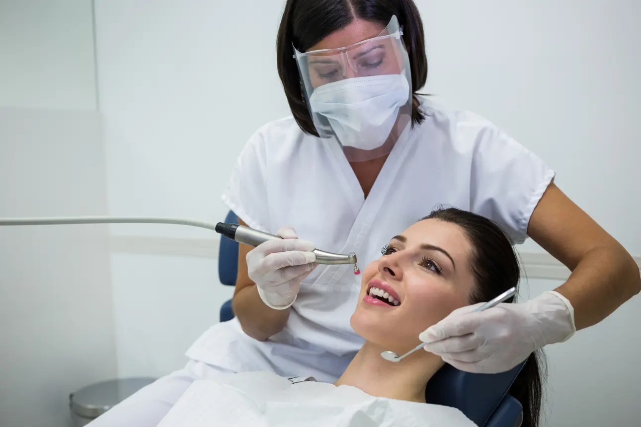 Odontóloga atendiendo a una paciente sonriente en el consultorio